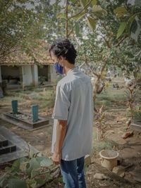 Rear view of young man standing against plants