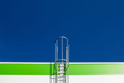 Low angle view of ladder against clear blue sky