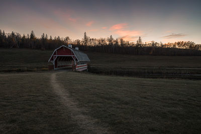 House on field against sky during sunset