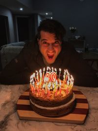 Portrait of mature man with mouth open by birthday cake on table