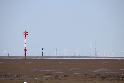 Windmills on beach against clear sky