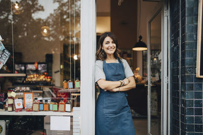 Portrait of confident female owner standing at entrance of deli