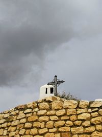 Low angle view of cross on roof of building against sky