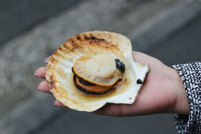 Close-up of hand holding grilled scallp