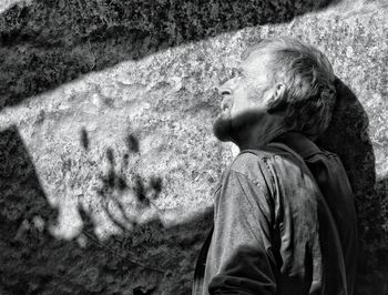 Low angle view of man looking up against wall on sunny day