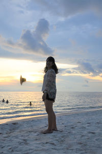 Full length of man standing on beach against sky during sunset