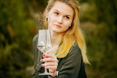 Young woman holding wineglass standing outdoors