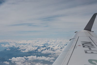 Aerial view of airplane flying over landscape against sky