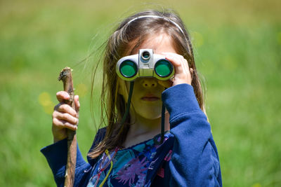 Portrait of baby girl holding camera while standing outdoors