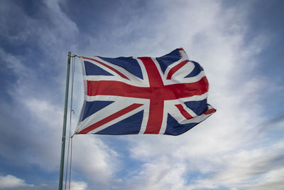 Union jack flag blowing in the wind against a blue sky.