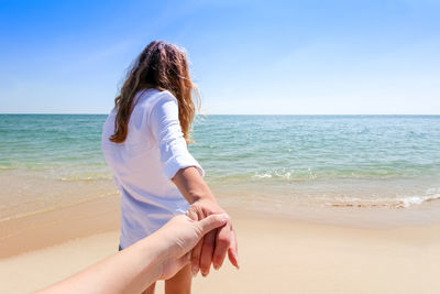 Midsection of woman at beach against sky