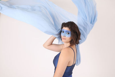 Side view portrait of female model with blue face paint against white background