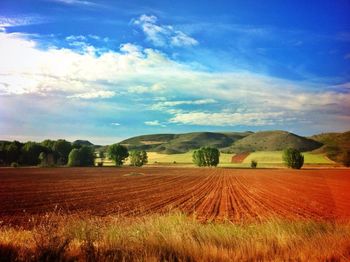 Scenic view of field against cloudy sky