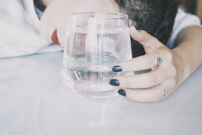 Midsection of person holding glass of water