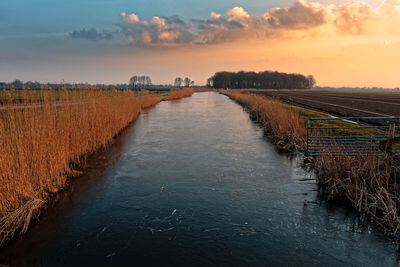 Scenic view of agricultural landscape against sky during sunset