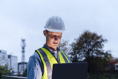 Engineer wearing hardhat using laptop