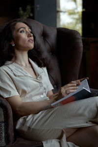 Young woman using mobile phone while sitting on sofa at home