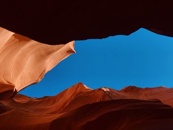 Low angle view of rock formations at desert against clear blue sky