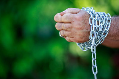 Cropped hands of man tied with chain