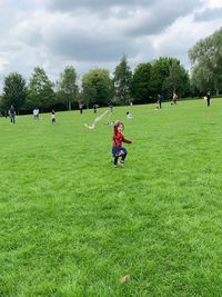 People playing on field against trees