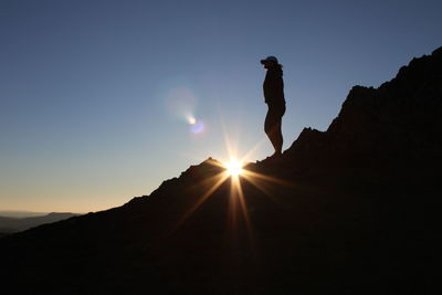 Silhouette man on mountain against sky during sunset