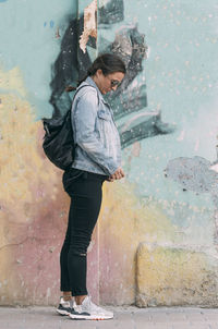 Full length of woman standing against wall