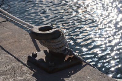 High angle view of rope tied to bollard at harbor