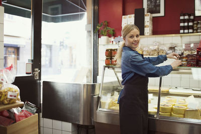 Side view portrait of confident saleswoman standing working in supermarket