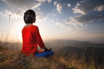 Woman sits in a lotus position and meditates at sunset in the grass in the mountains, balance and