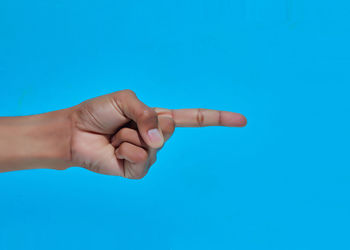 Close-up of person hand against blue background