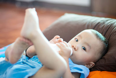 Portrait of cute boy lying on bed at home