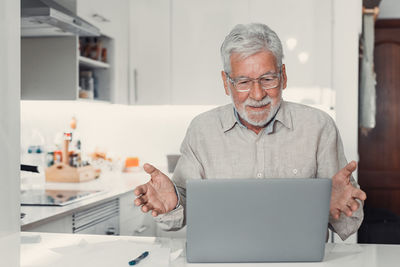 Portrait of senior man using mobile phone while sitting at home