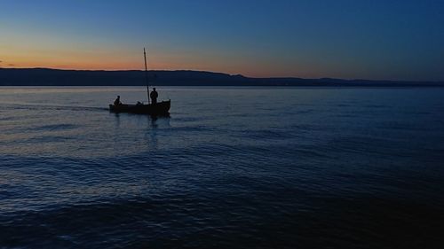 Silhouette sailboat sailing on sea against sky at sunset