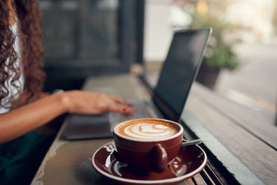 Midsection of woman using laptop on table