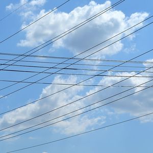 Low angle view of electricity pylon against cloudy sky