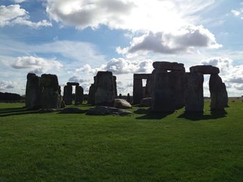 Built structure in field against cloudy sky