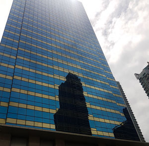 Low angle view of modern glass building against sky