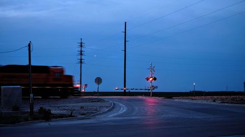 Railroad tracks by road against sky at dusk
