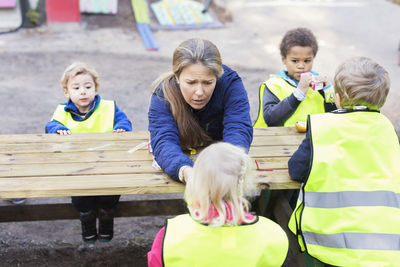 Children in protective jackets sitting with children at table