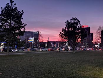 City street by buildings against sky during sunset