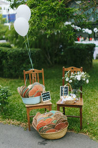 A wedding signage surrounded by balloons, fans, bug spray and flowers on chairs
