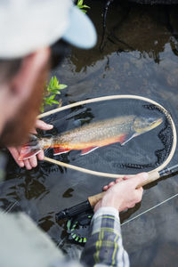 Man holding fishing net with fish in water