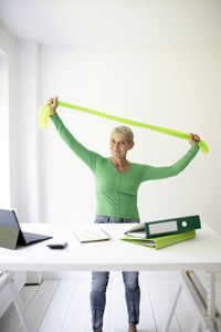 Rear view of woman with arms raised standing against white background