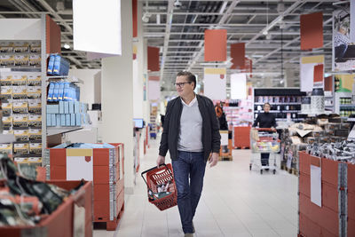 Mature man walking with basket in supermarket