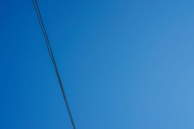 Low angle view of power lines against blue sky