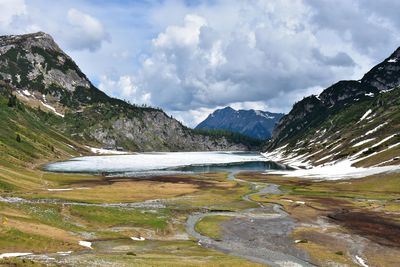 Scenic view of river by mountains against sky