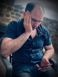 Man using smart phone while sitting on chair