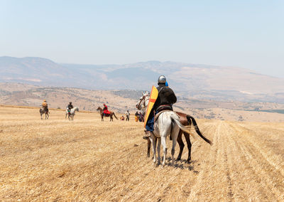 People riding horse on field against sky