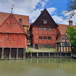 Buildings by river against sky