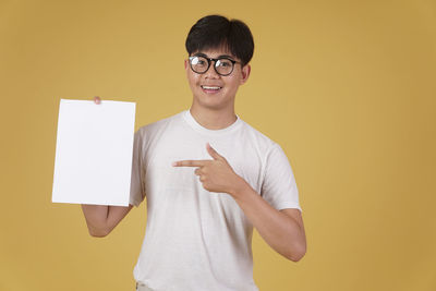 Portrait of smiling man standing against yellow wall